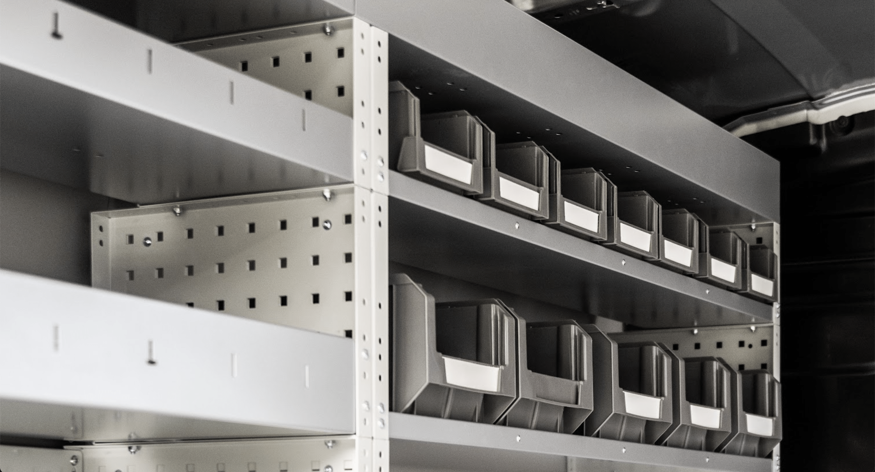 Efficiënt ingerichte bestelwagen Professionele inrichting van een bestelwagen met gelabelde opbergbakjes en metalen legplanken, gerealiseerd door Avietech